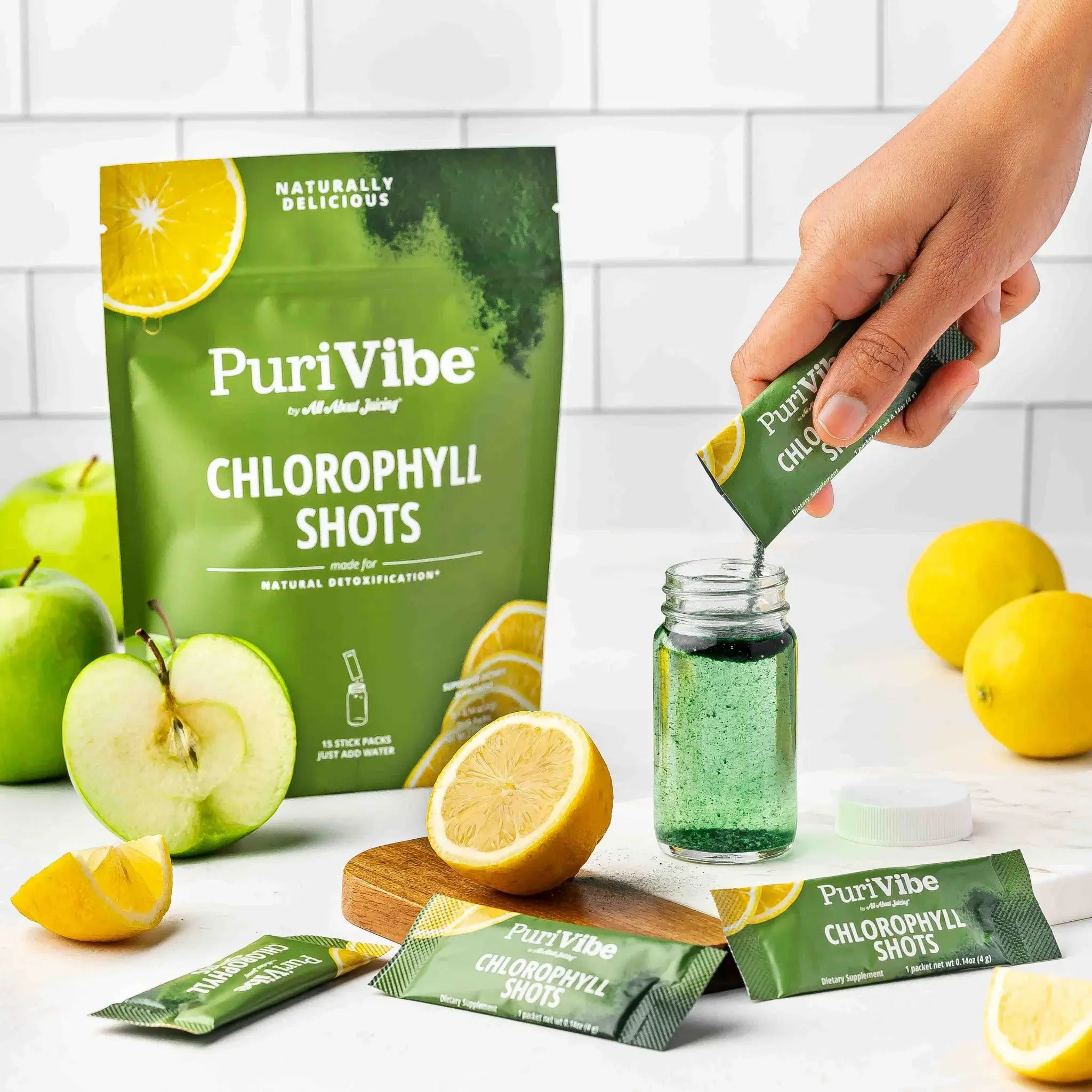 PuriVibe Chlorophyll Shots being poured into a jar with green packets and lemons on a white surface.